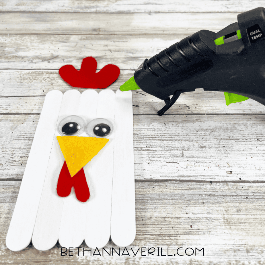 Chicken face forming with googly eyes, yellow beak, and red comb glued on.