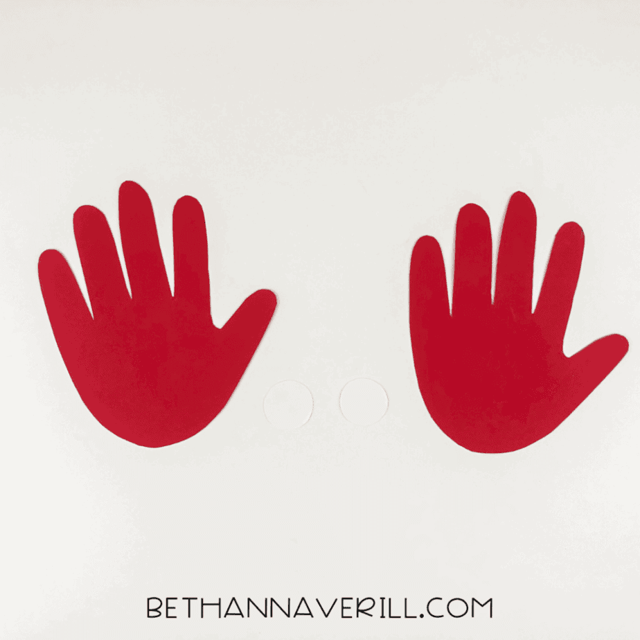 Two red handprints and two small white paper circles cut out