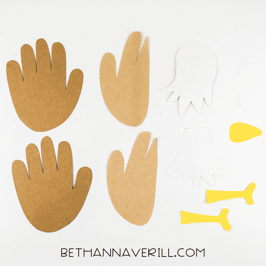 Cut-out handprints and eagle body pieces in brown, white, and yellow paper