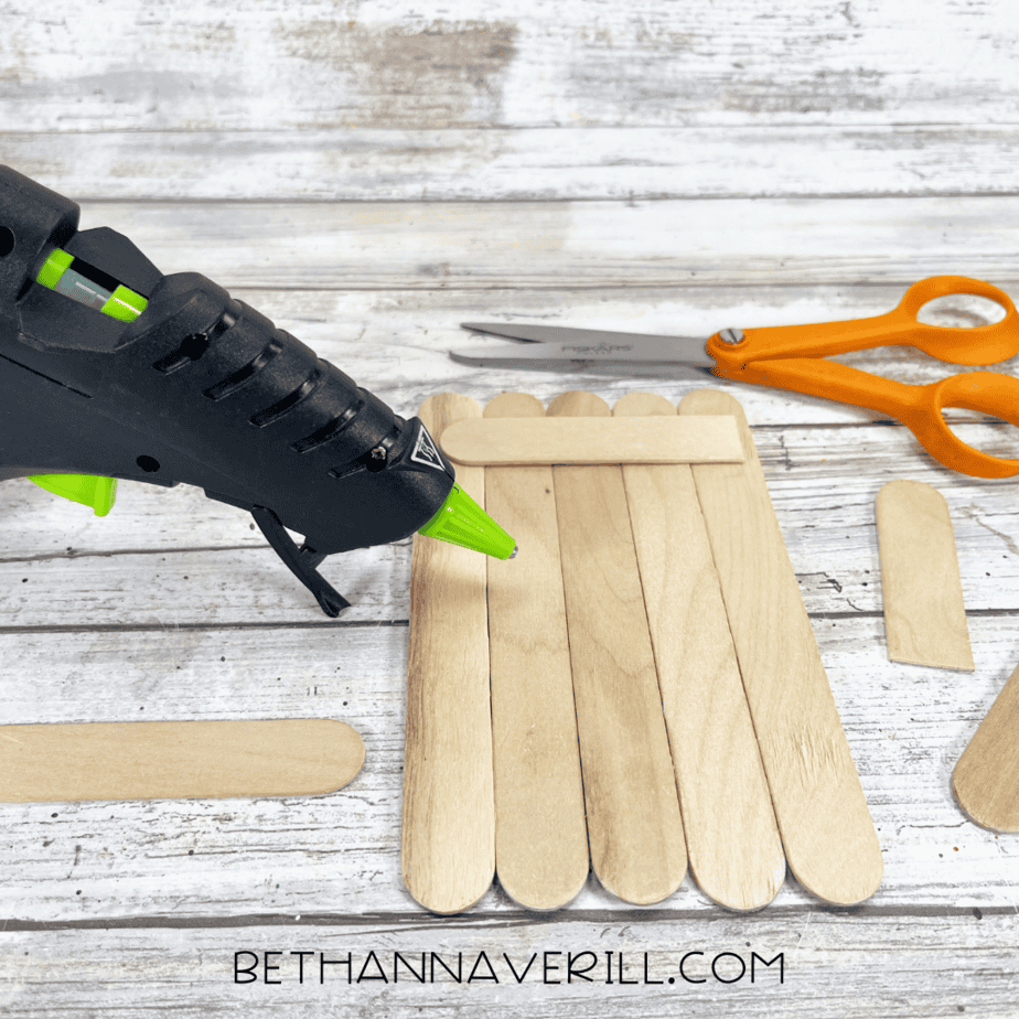 Popsicle sticks glued together with hot glue gun shown in process.