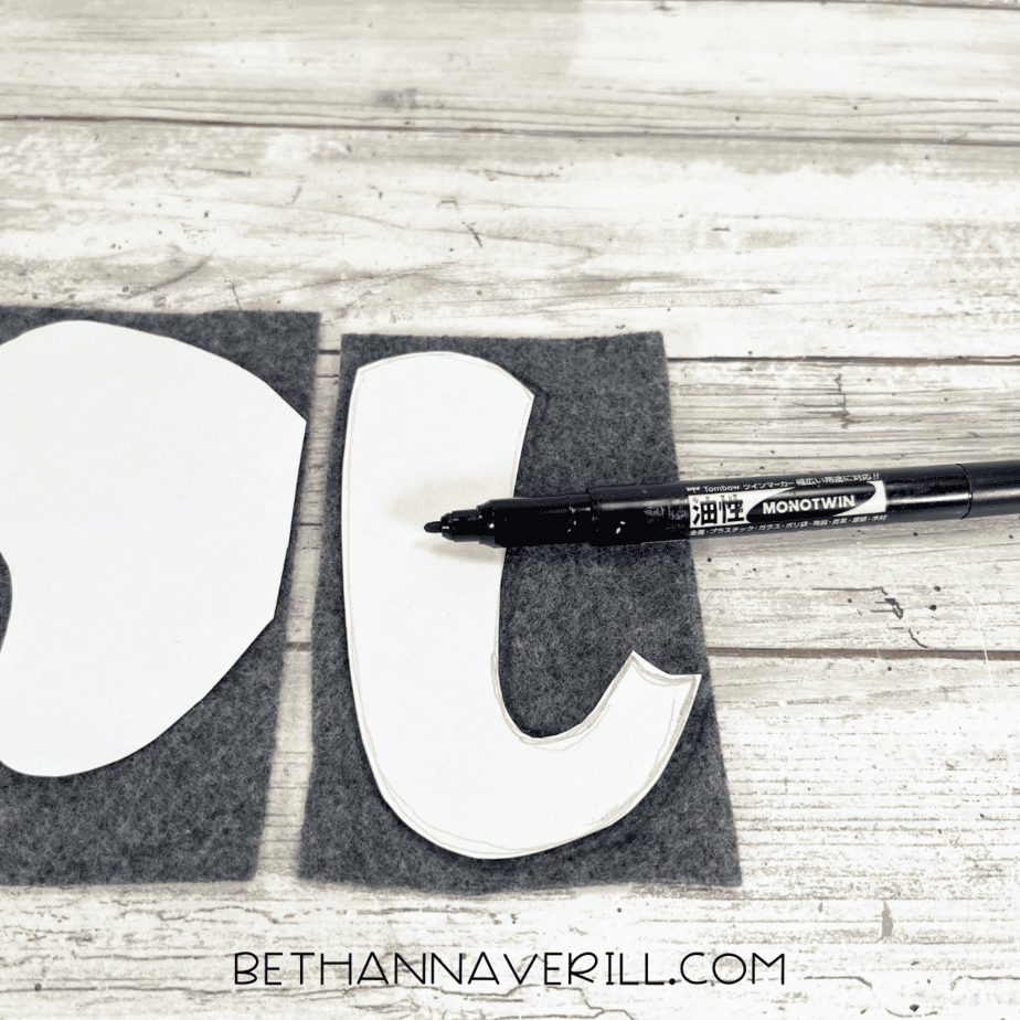 Elephant ear and trunk templates being traced onto grey felt with black marker.