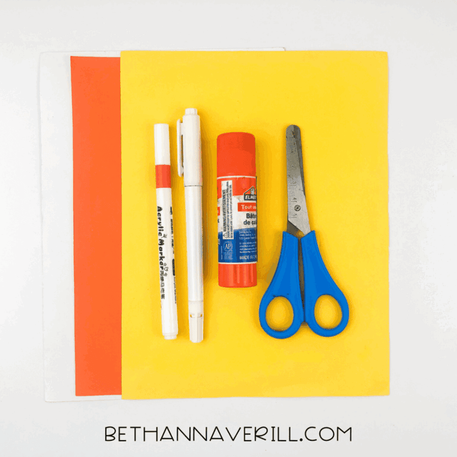 Materials for fish handprint craft: glue stick, orange and yellow construction paper, scissors, and markers