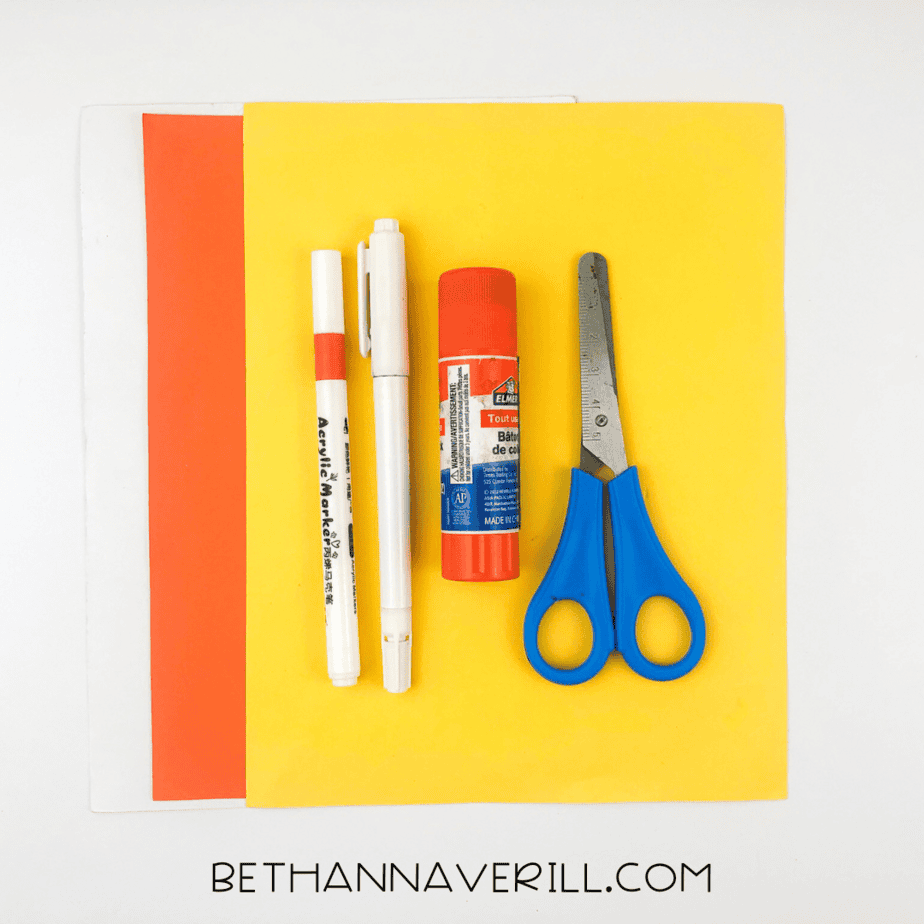 Materials for fish handprint craft: glue stick, orange and yellow construction paper, scissors, and markers