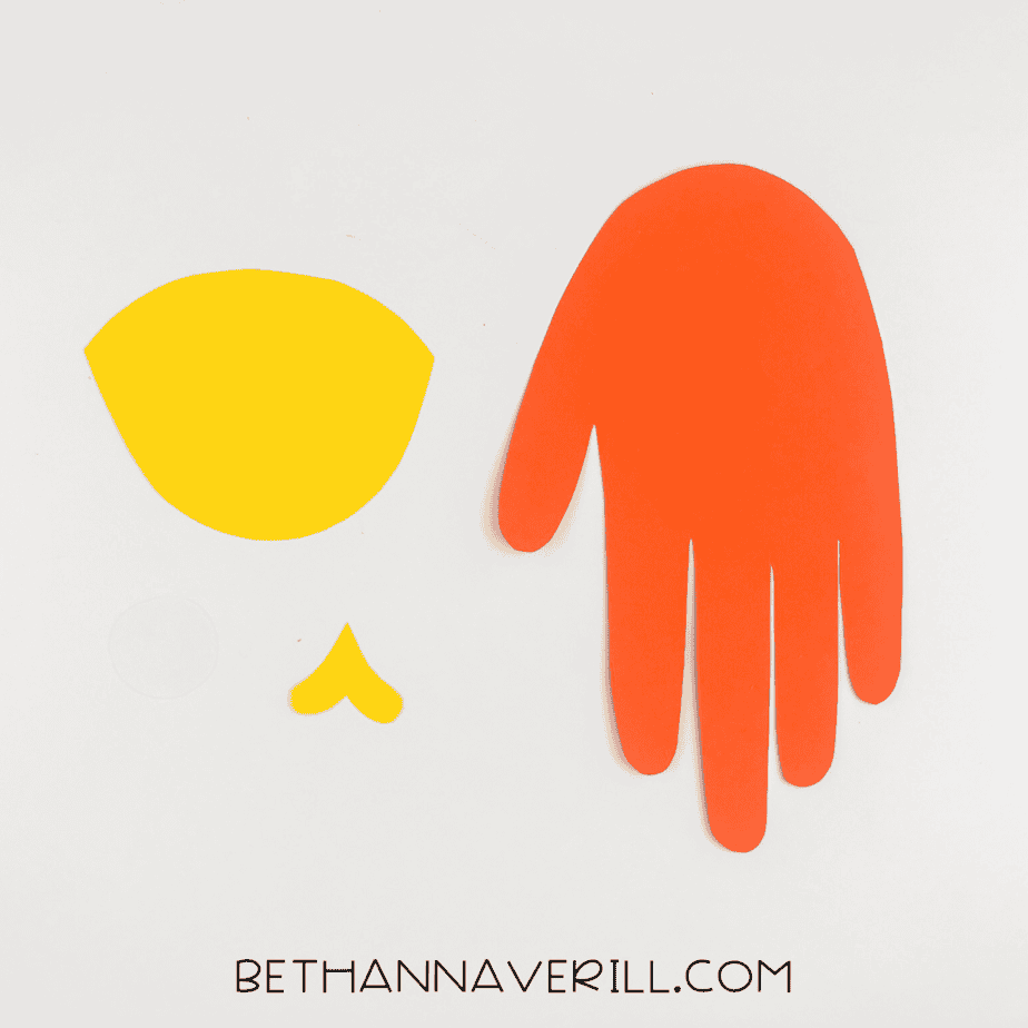 Cut-out pieces for fish handprint craft: orange handprint, yellow face, fin, and white circle for eye