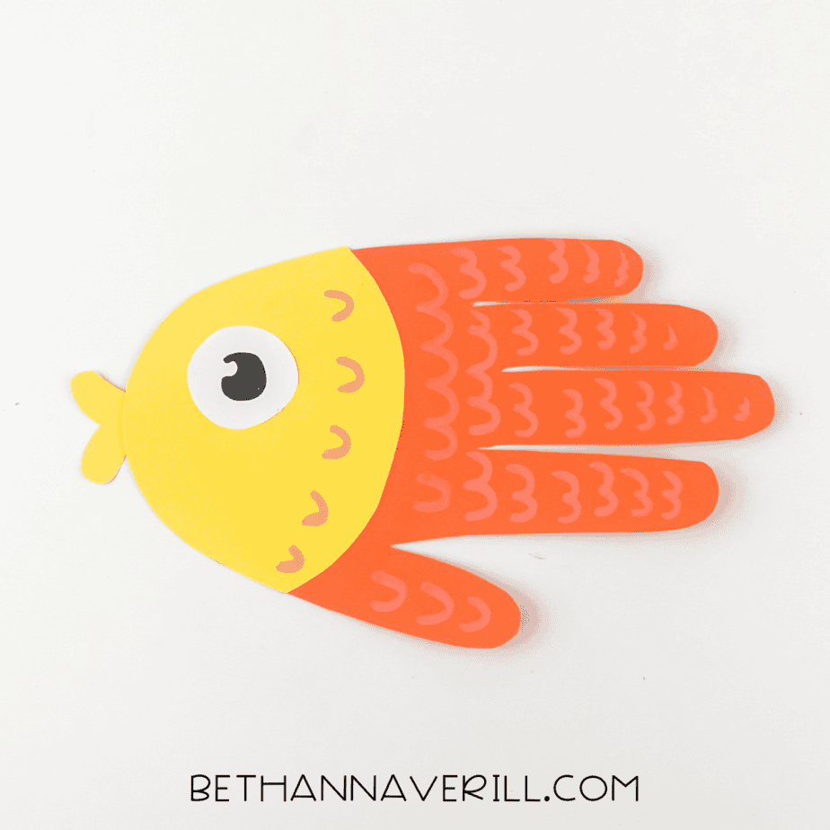 Close-up of finished fish handprint craft with yellow face and orange body