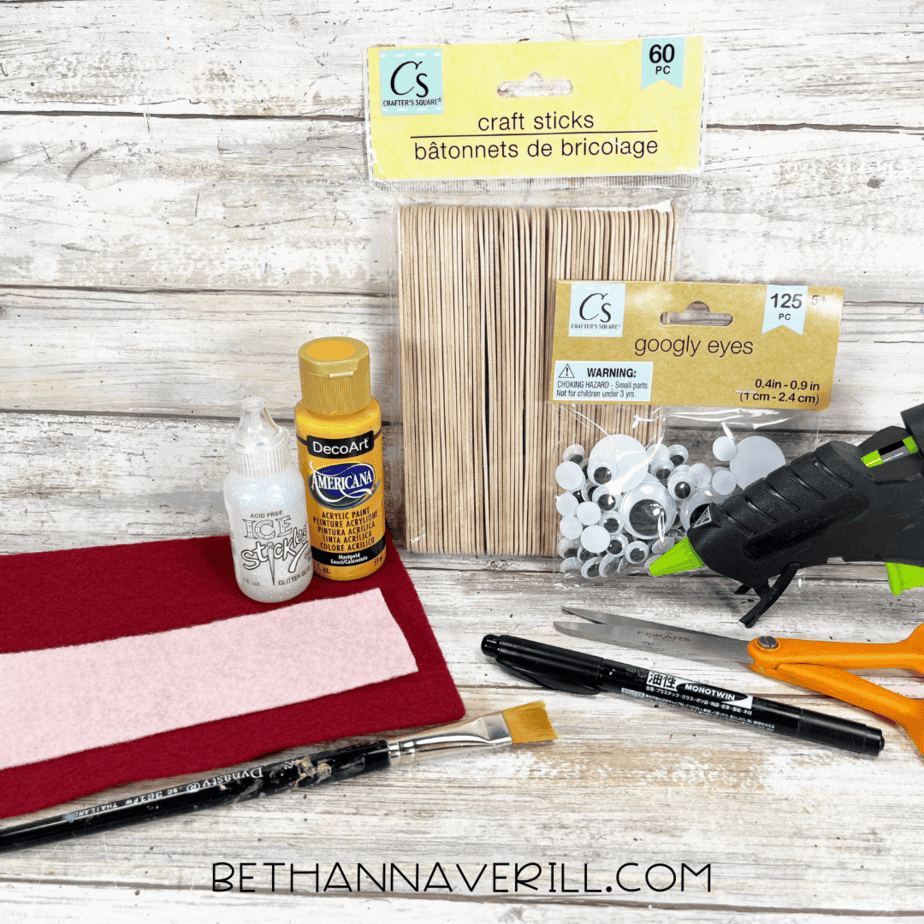 Materials for French Fries Popsicle Stick Craft including craft sticks, yellow paint, felt, googly eyes, glue gun, scissors, and paintbrush.