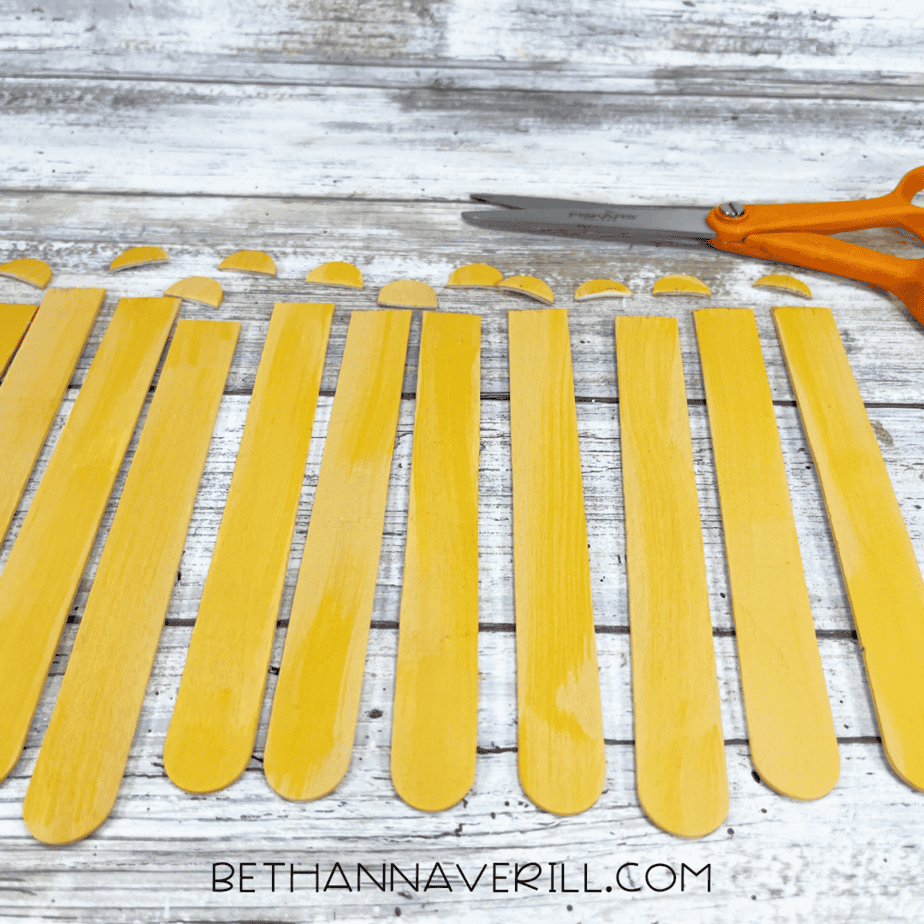 Yellow-painted craft sticks with rounded tops trimmed off to look like fries.