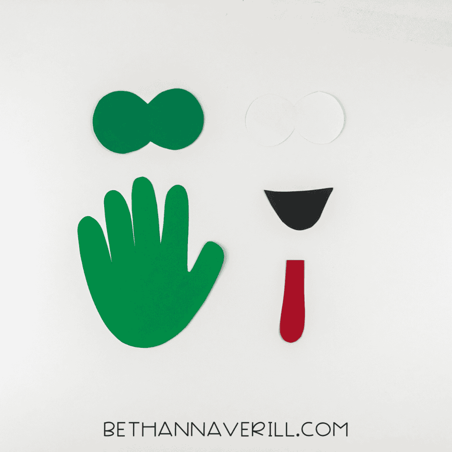 Materials for frog handprint craft: glue stick, scissors, black marker, and colored paper