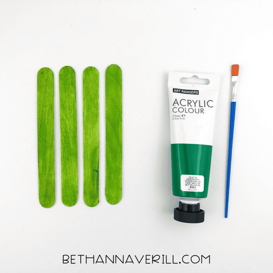 Four popsicle sticks painted green with acrylic paint.