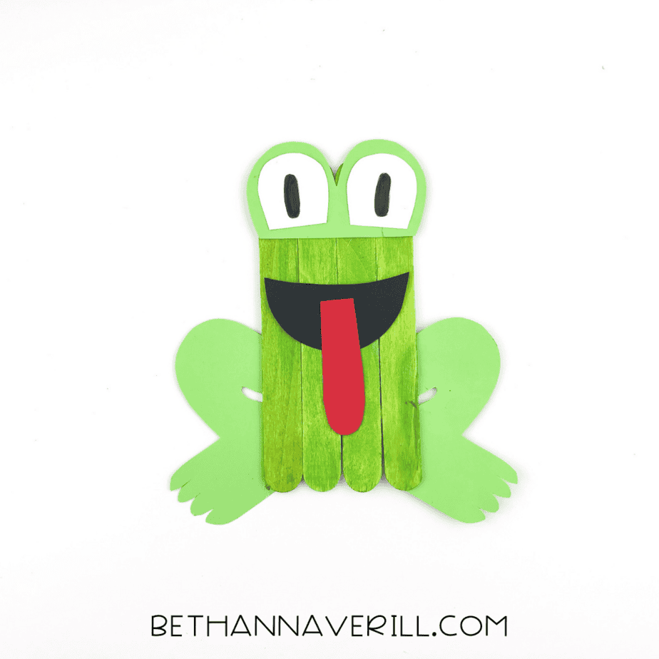 Completed frog popsicle stick craft with eyes and tongue.