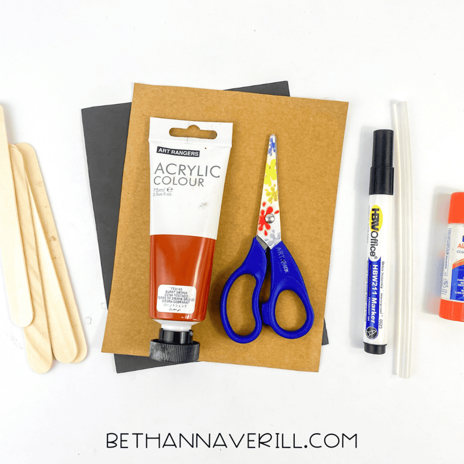 Craft supplies for goat popsicle stick craft including paint, paper, popsicle sticks, scissors, glue, and marker.