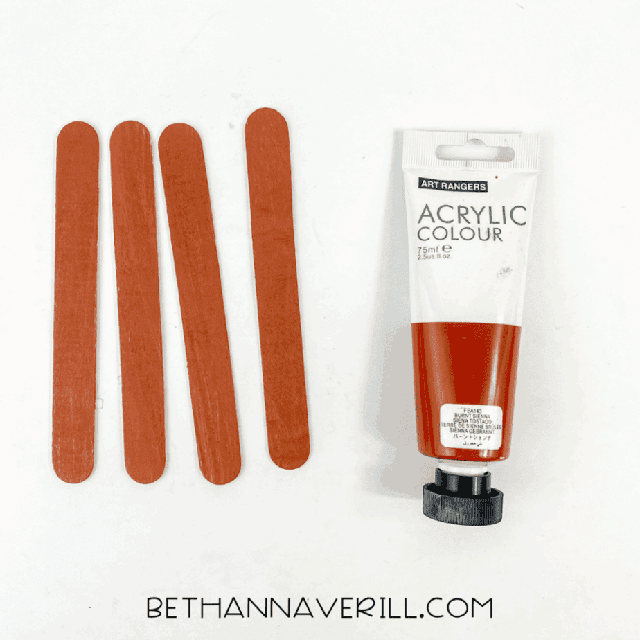 Four popsicle sticks painted brown with acrylic paint.