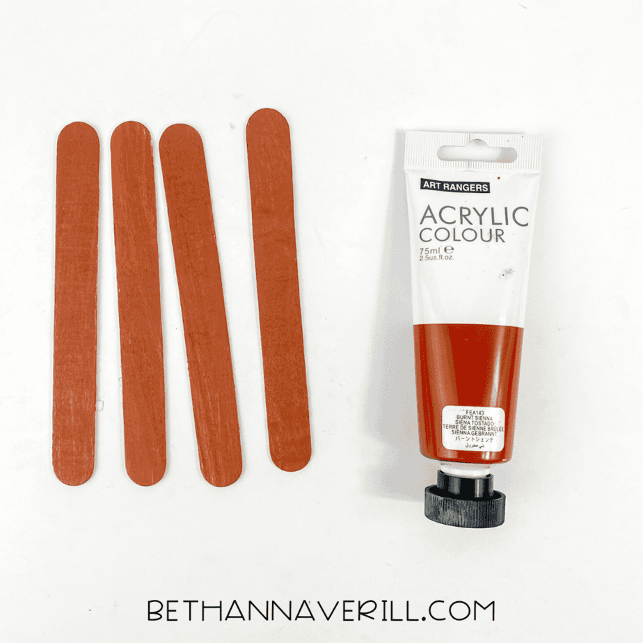 Four popsicle sticks painted brown with acrylic paint.