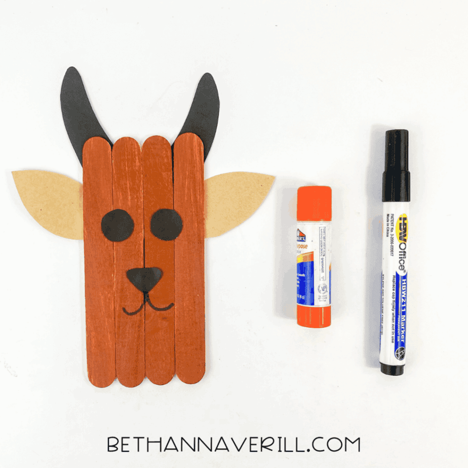 Goat popsicle stick craft with horns, ears, nose, and a drawn smile