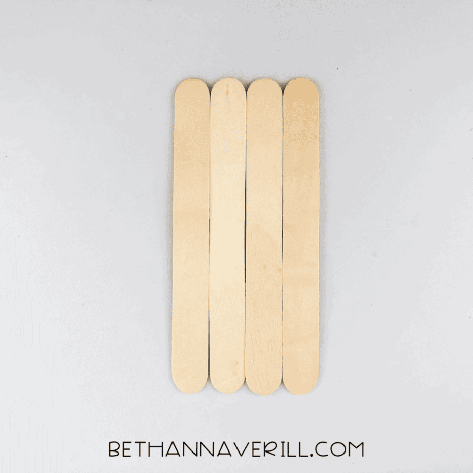 Four plain popsicle sticks lined up side by side on a white background.