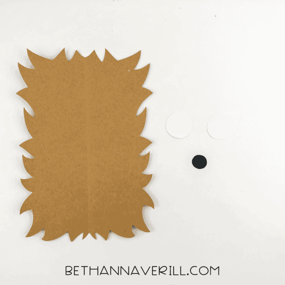 Brown spiky paper body, white eye circles, and a black nose cut out for the hedgehog