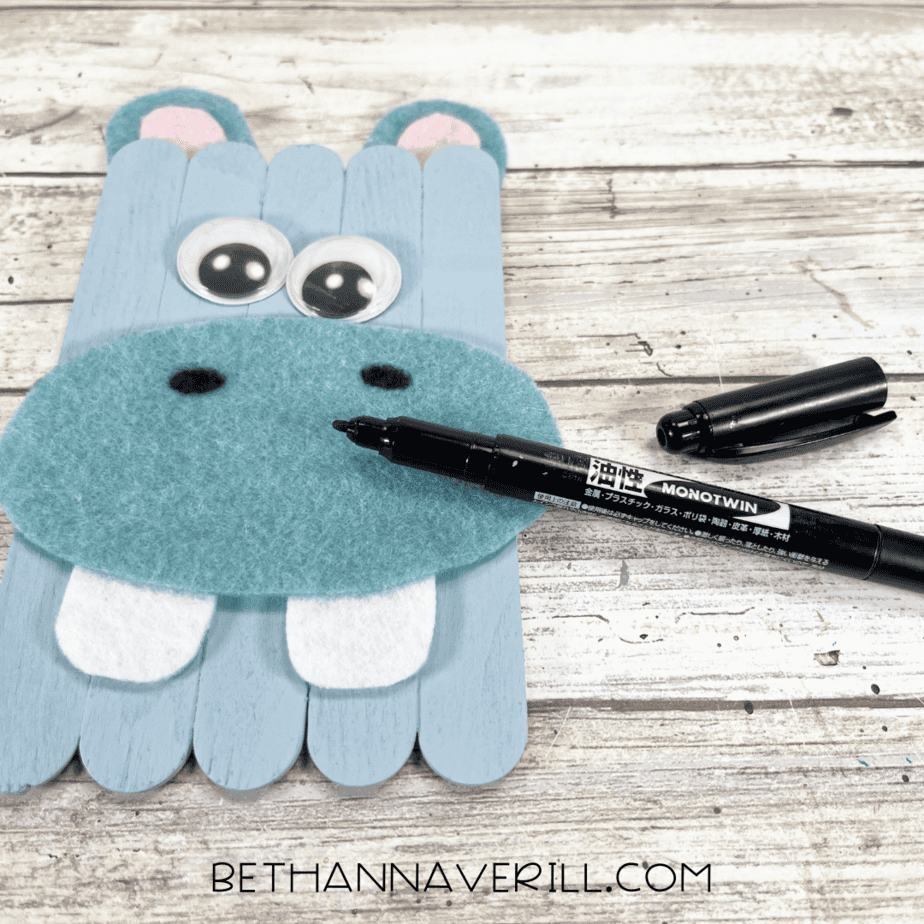 Black marker being used to draw hippo nostrils on the felt nose.