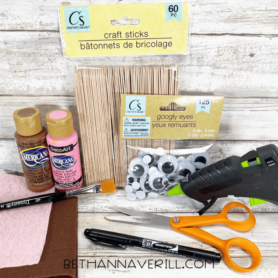 Craft sticks, felt, googly eyes, glue gun, paint, and scissors laid out for horse popsicle stick craft.