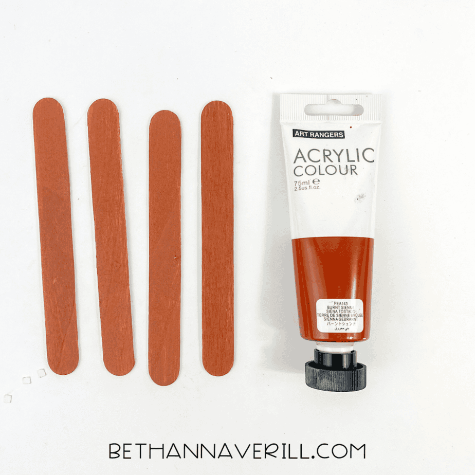 Four popsicle sticks painted brown with acrylic paint.