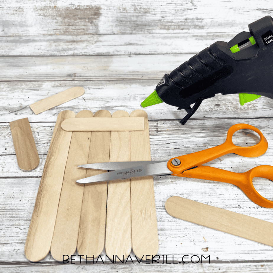 Five craft sticks glued together with support stick across top using hot glue gun.