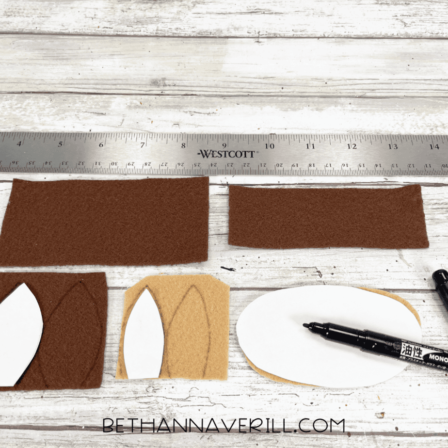 Paper templates on brown and tan felt with ruler and black marker for tracing ears and muzzle.