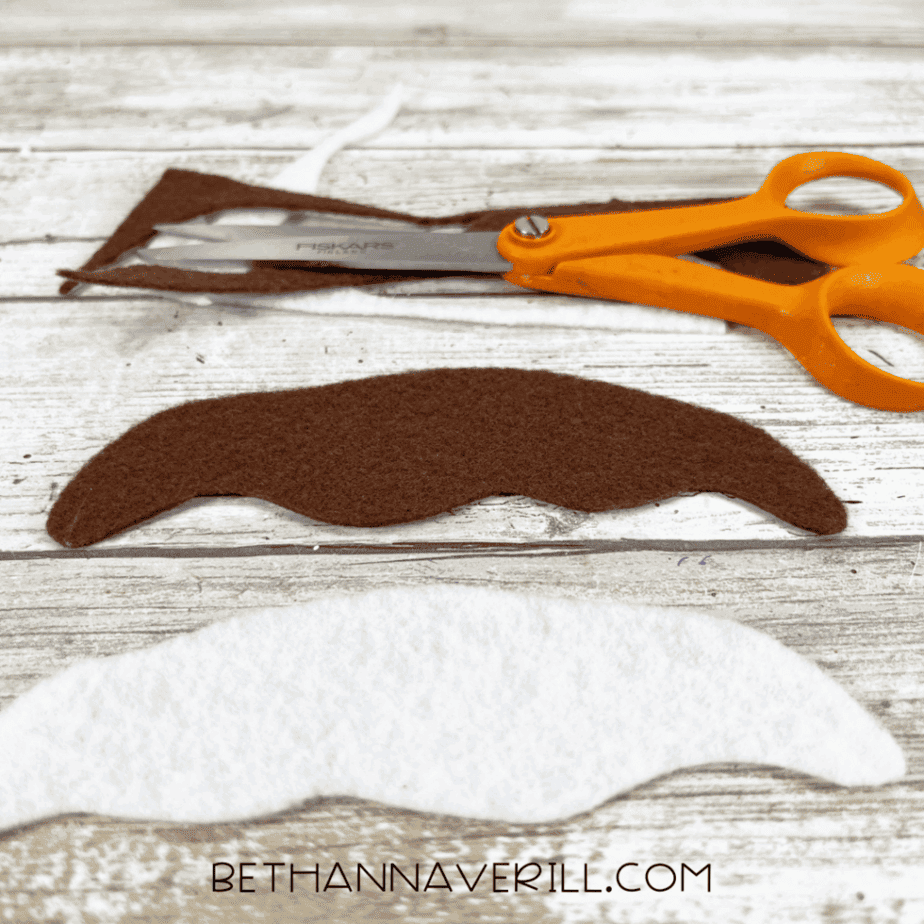 Brown and white felt scoops cut out with orange scissors resting nearby.