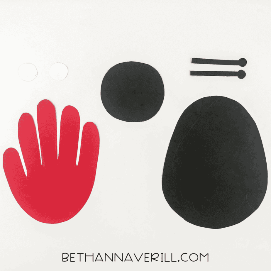 Cut-out pieces: red handprint, black body and head, white circles for eyes, and black antennae