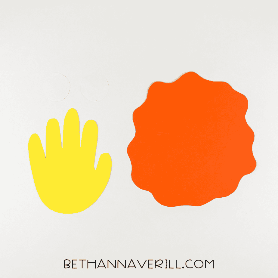 Cut-out pieces for lion craft: yellow handprint, orange mane, and two white eye circles.