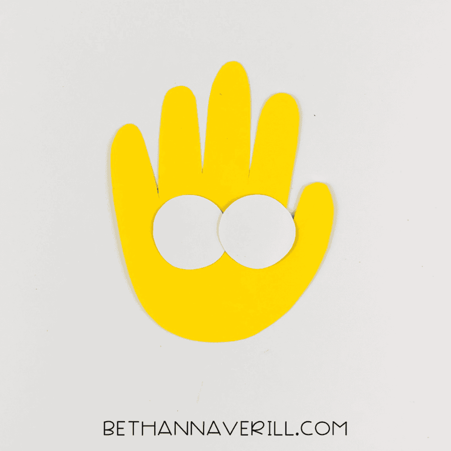 Yellow handprint with two white paper circles glued on as eyes.