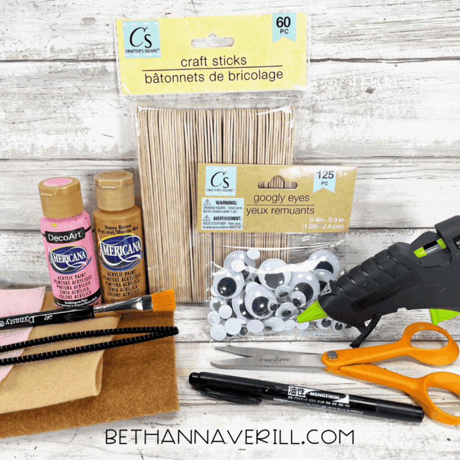 Lion popsicle stick craft supplies including paint, felt, googly eyes, scissors, glue, and craft sticks.