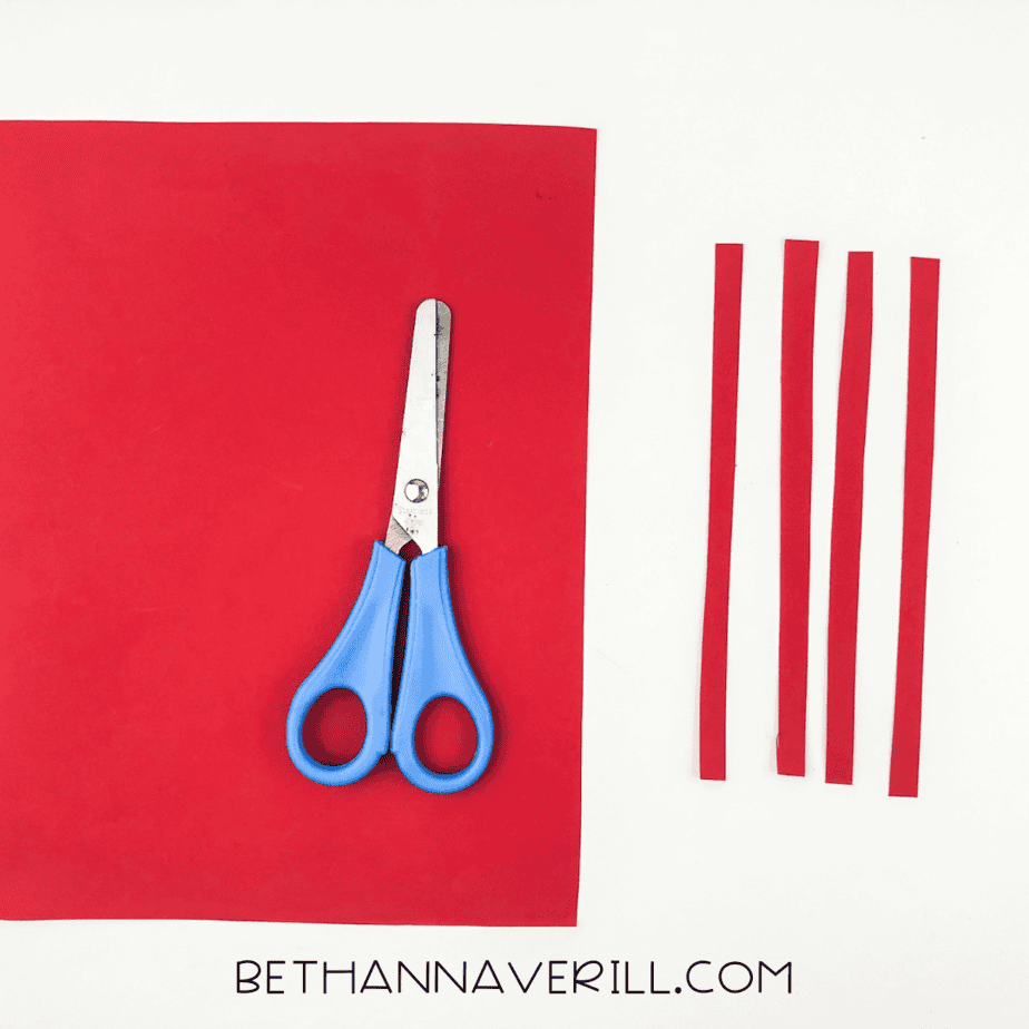 Red paper strips and scissors laid out for lobster legs.
