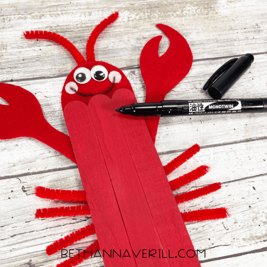 Black marker adding face details to lobster craft