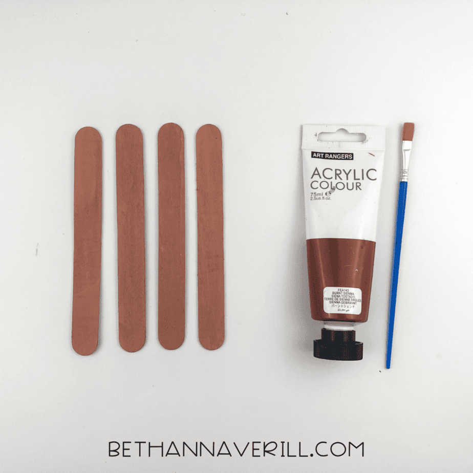 Painted brown popsicle sticks with brown acrylic paint and paintbrush.