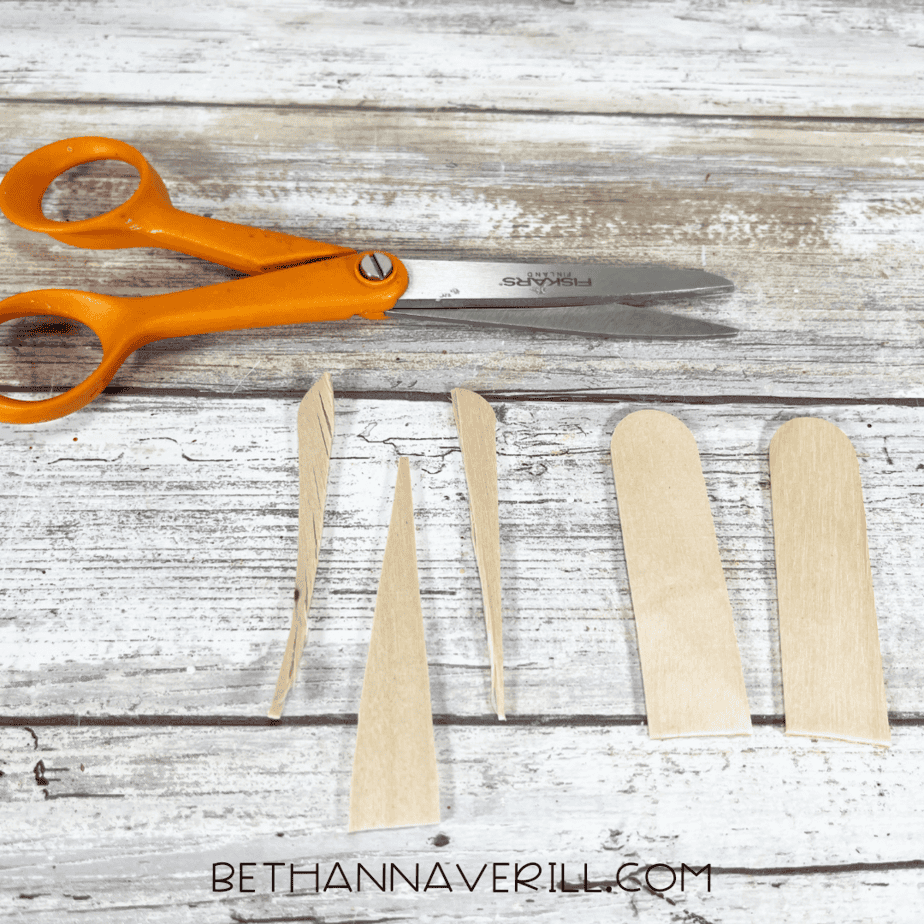 Cut pieces of craft sticks shaped like flippers and a narwhal tusk.