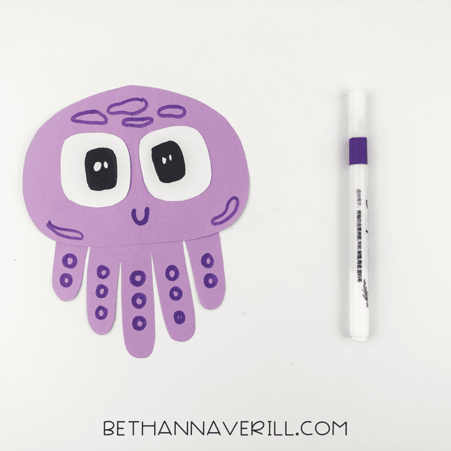 Smiling face drawn with added details and marker next to craft
