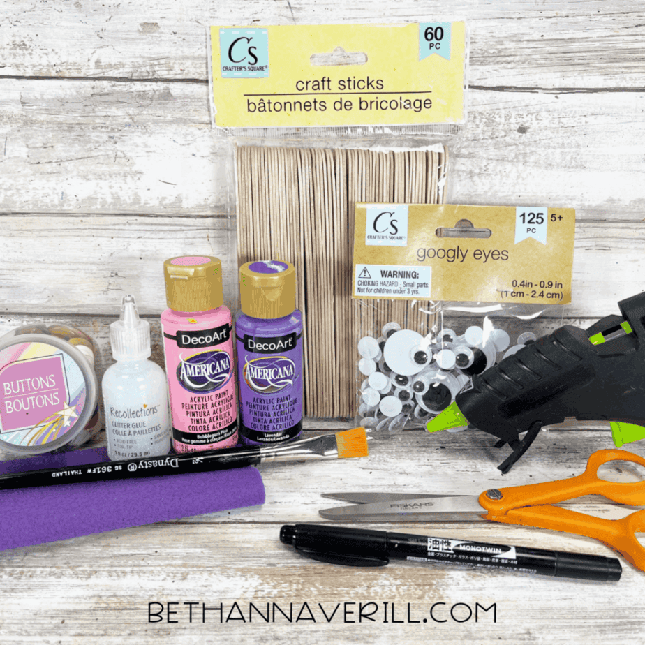 Supplies for octopus popsicle stick craft including craft sticks, paint, felt, googly eyes, and glue gun.