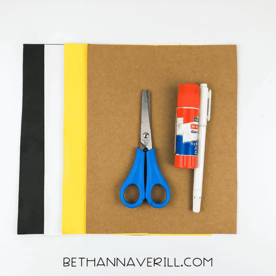 Materials for owl handprint craft: brown, yellow, white, and black paper with scissors and glue