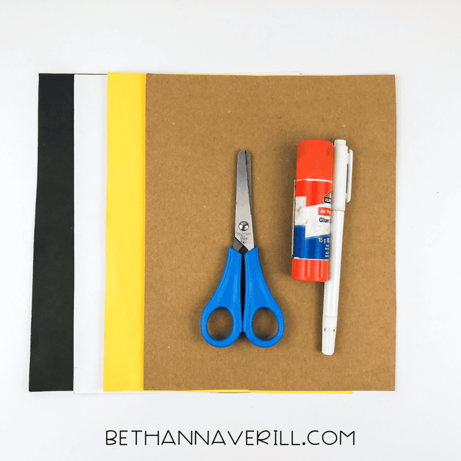 Materials for owl handprint craft: brown, yellow, white, and black paper with scissors and glue