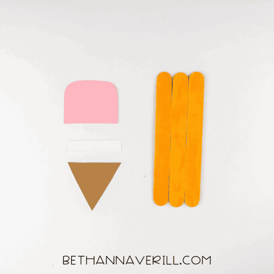 Cut pieces of pink, white, and brown paper for the pencil parts next to orange craft sticks.