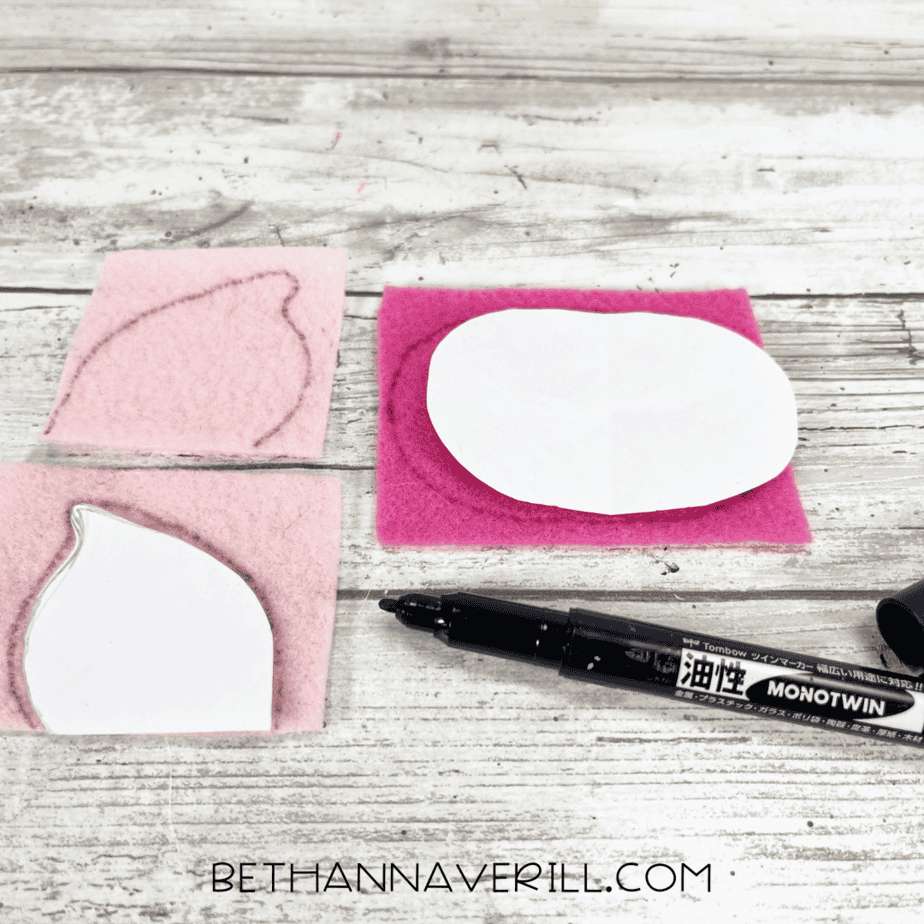 Pink felt with paper templates and a black marker used for tracing shapes.