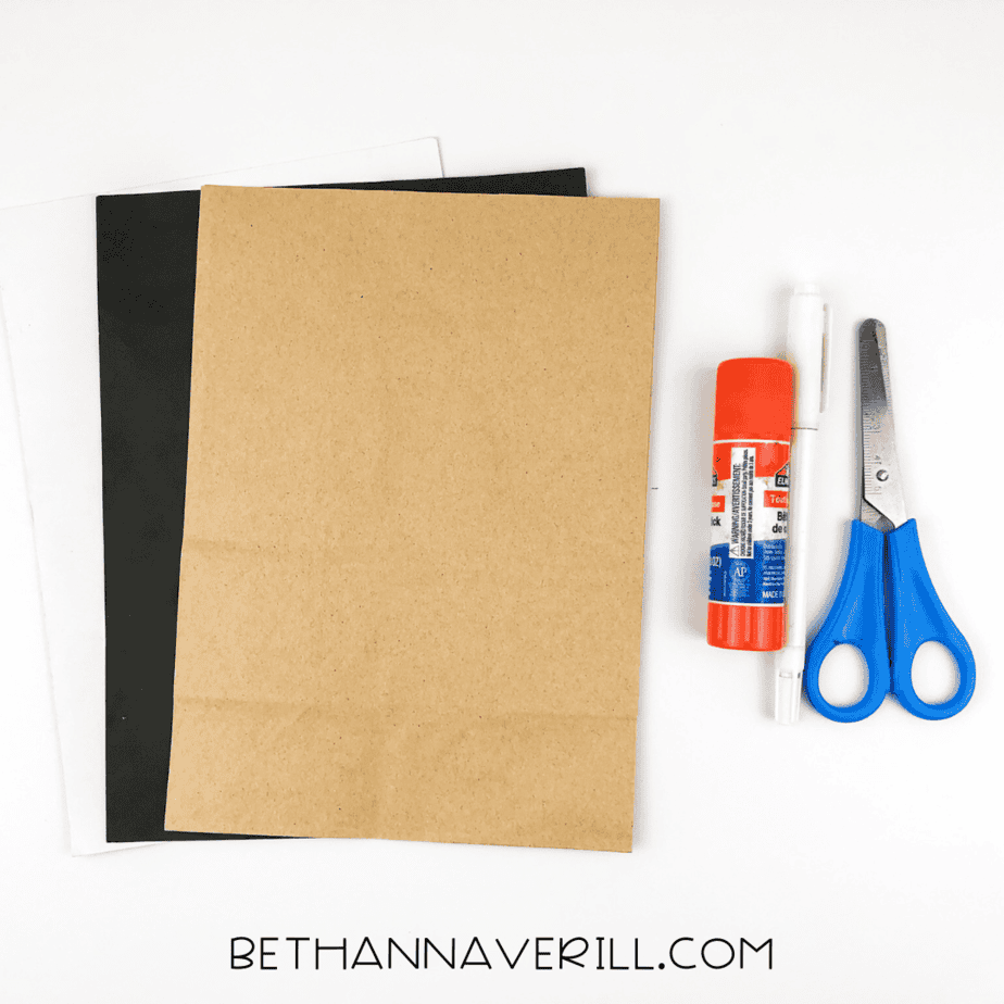 Materials needed for the pirate handprint craft: tan, black, and white construction paper, glue stick, pencil, scissors, and black marker.