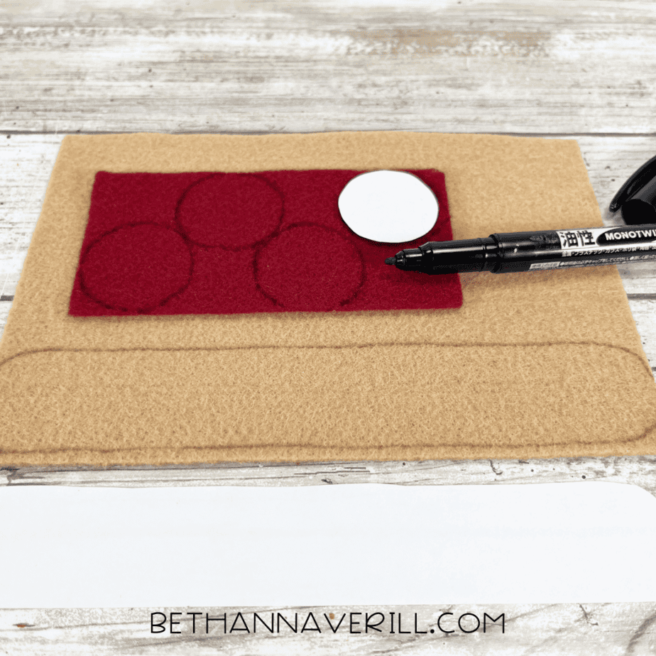 Tracing felt shapes for toppings — red felt circles for pepperoni and tan felt for the crust marked with a black marker.