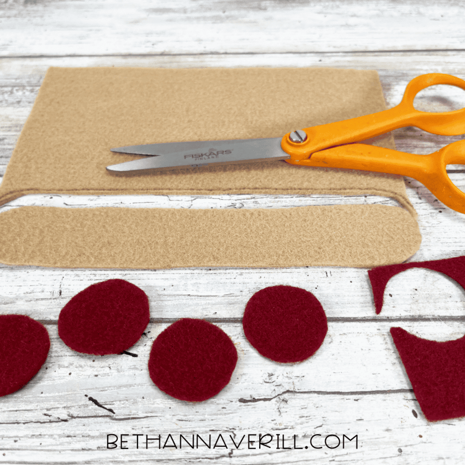 Cut felt toppings — tan felt crust strip and red felt pepperoni circles cut out and ready to attach.