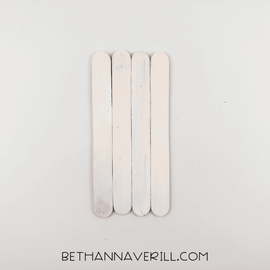 Four popsicle sticks glued into a panel and painted white.