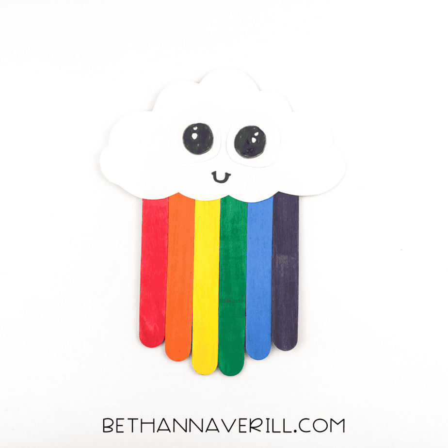 black marker used to add details to rainbow craft with a smiling cloud face.