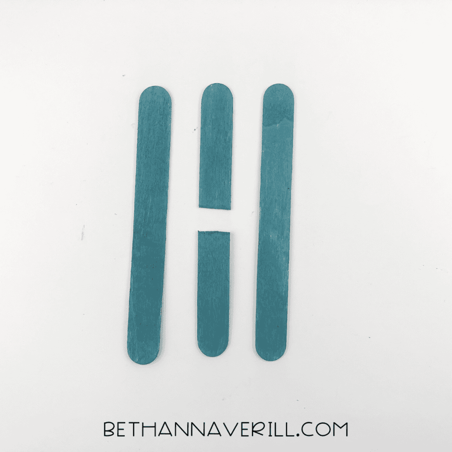 Three craft sticks painted blue, one cut in half.