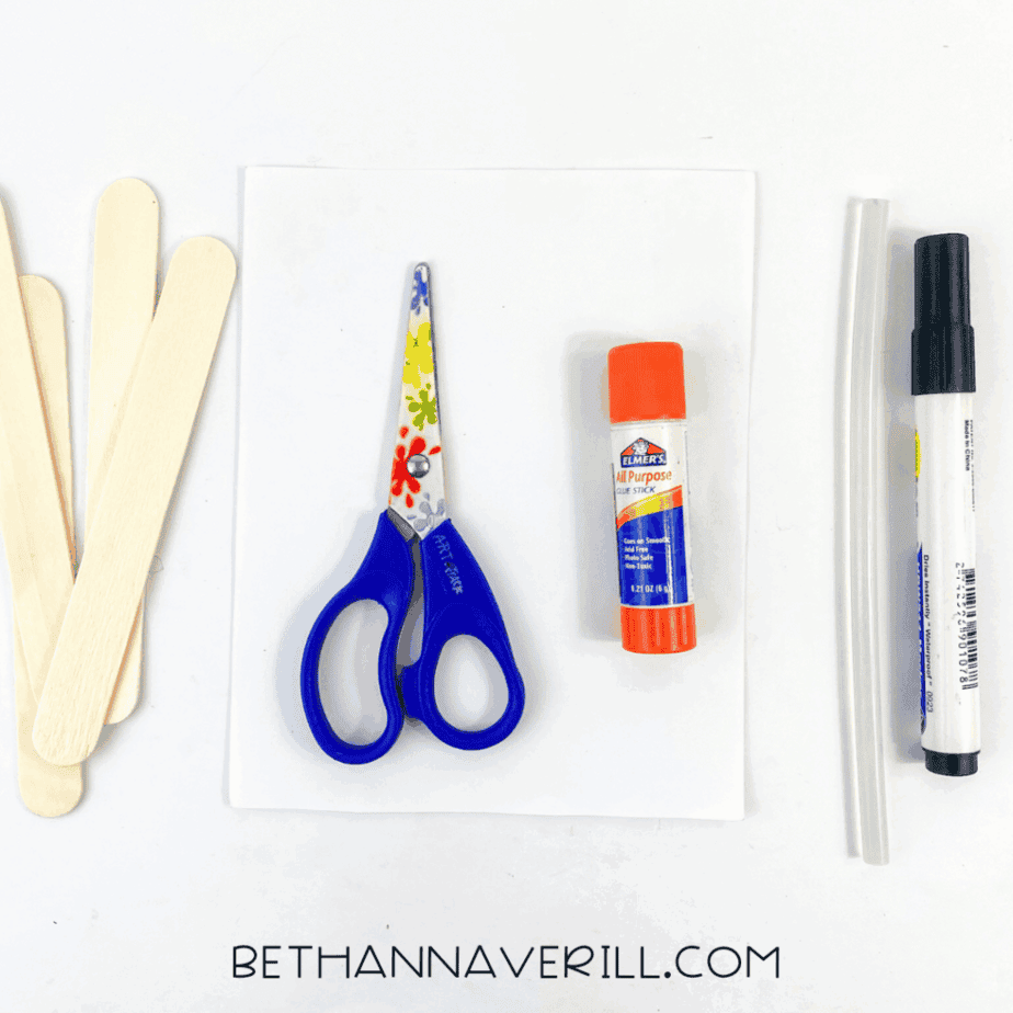 Materials laid out: popsicle sticks, glue stick, scissors, marker, and white paper