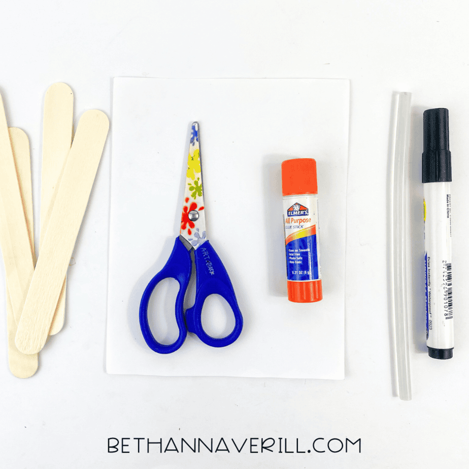 Materials laid out: popsicle sticks, glue stick, scissors, marker, and white paper