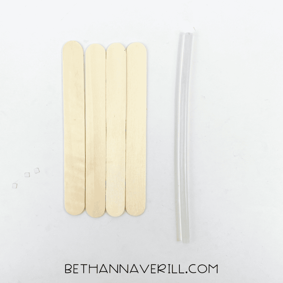 Five craft sticks lined up with tape and a glue stick