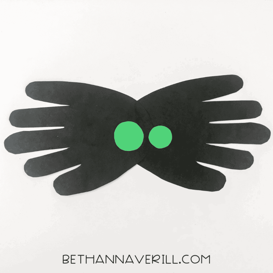 Green paper eyes glued to center of black spider body
